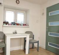 Dining room in a family house with a white table, refrigerator, and wood-patterned flooring.