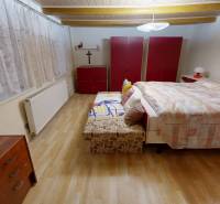 Bedroom in a family house with a bed, wardrobes, and a floor with a wooden decor.