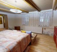 A room in a family house with a wooden decor floor, a bed, and a red wardrobe.