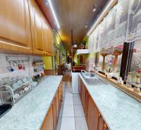 A kitchen in a family house with cabinets, appliances, and a view of the garden through a large window.