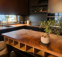 A kitchen in a 2-room apartment with a wooden decor floor and a black kitchen unit.