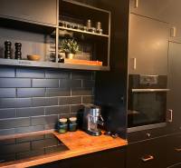 A kitchen with black cabinets in a 2-room apartment and a floor with a wooden decor.