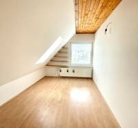 Attic room in a family house with a wooden decor floor and a skylight.