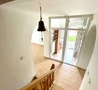 Staircase with a wooden decor floor, entrance door, and doorbell in a family house.