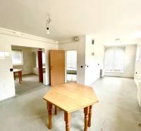 A spacious room with wooden tables and radiators in a family house.