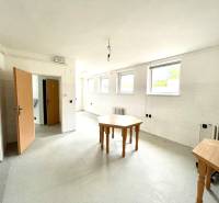 Interior of a family house with an empty room, tables, and white walls.