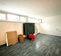 A room in a family house with a wooden decor floor, windows, and cardboard boxes.