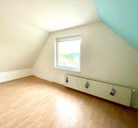 Attic room with a window and a wooden decor floor in a family house.