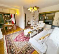 The interior of a cabin with a spiral staircase, a television, and a table on a floor with a wooden decor.