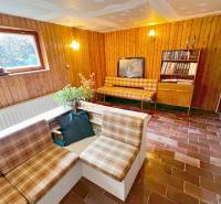 Interior of a cottage with a living room, rustic furniture, and brick flooring.