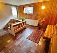 Living area in a cabin with brick flooring and wooden decor on the walls.