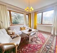 Bright living room with wood-patterned flooring, carpet, white furniture, large windows.