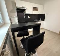 A kitchen with seating and a wooden decor floor in a studio apartment.