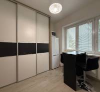Furnishing of a studio apartment, sliding wardrobe, tall refrigerator, table with two chairs.
