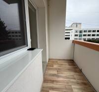 A balcony in a one-room apartment with a wooden decor floor.