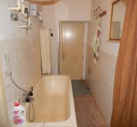 A bathroom in a family house with an older bathtub and tiles on the walls.