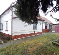 A family house in Kravany nad Dunajom with a garage, next to it a sidewalk and a grassy area.