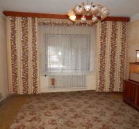 A room in a family house with floral patterned wallpaper and a central chandelier.