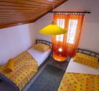 Double room in a holiday apartment with colorful textiles and wooden ceiling paneling.