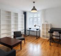 Interior of a 2-room apartment with a wooden decor floor, large shelves, and modern furniture.