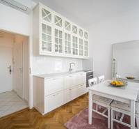 A kitchen in a one-room apartment with a wooden decor floor and a dining table.