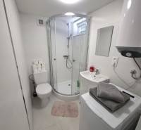 A bathroom with a bathtub, washing machine, boiler, and sink in a cottage. Minimalist design.