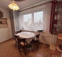 Dining area in a 2-room apartment with wood-patterned flooring, table, chairs, curtains.
