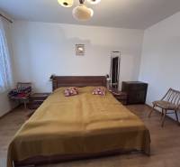 Bedroom in a 2-room apartment with a bed, chairs, and a wooden decor floor.