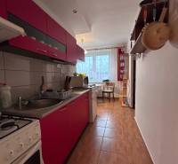 A kitchen in a 2-room apartment with red cabinets and a wood-patterned floor.