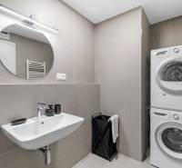 Bathroom in a 2-room apartment with a sink, washing machine, and dryer. Concrete tiles.