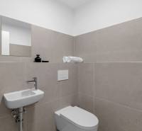 Bathroom in a 2-room apartment with a sink, toilet, and beige tiles.