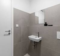 Bathroom in a 2-room apartment with a small sink, white tiles, and a mirror.
