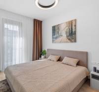 A bedroom with a large bed, curtains, and a wooden decor floor in a 2-room apartment.