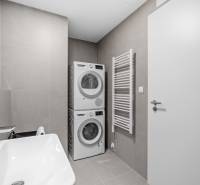 Bathroom in a 2-room apartment with a sink, washing machine, and dryer, tiled walls.