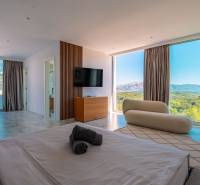 Bright bedroom in a villa with a view through large windows, wooden decor flooring.