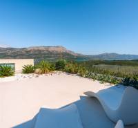 The terrace of the villa in Korčula with a view of the sea and surrounding mountains, surrounded by plants.