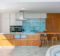 A kitchen in a villa with a wood-patterned floor, an island, and bar stools.