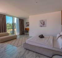 A bedroom in a villa with large windows and marble flooring, featuring stylish furniture.