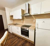 A kitchen in a 2-room apartment with a wood-patterned floor and white appliances.