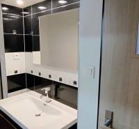 Bathroom with a sink and mirror, black tiles, space in an apartment, family house.