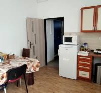Kitchen in a family house with a table, sink, refrigerator, and kitchen cabinets.