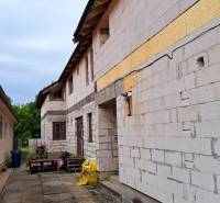An incomplete family house with white bricks, many wooden beams on the construction site.