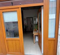 Wooden doors leading to the interior of a family house with a white floor and a table.