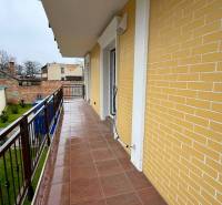 A balcony in a 3-room apartment in Komárno with a view of the courtyard and a brick facade.