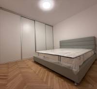 Bedroom in a two-room apartment with a wood-patterned floor and a large built-in wardrobe.