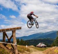 A cyclist is jumping on a track in Bystré, with a view of hills and cottages.