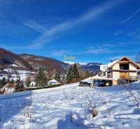A snowy landscape in Mýto pod Ďumbierom with a view of the mountains and a building on the property.