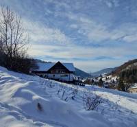 Snow-covered residential lands in Mýto pod Ďumbierom, surrounded by hills and forests.