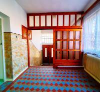 A hallway in a family house with patterned tiles, wooden doors, and curtains.