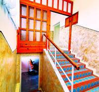 A colorful staircase leads to the upper floor of the family house, adorned with a wooden railing.